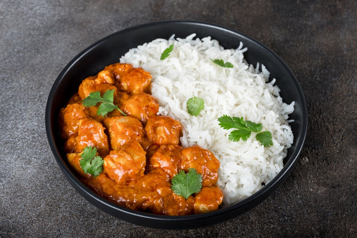Indian chicken butter masala curry with basmati rice on a dark background
