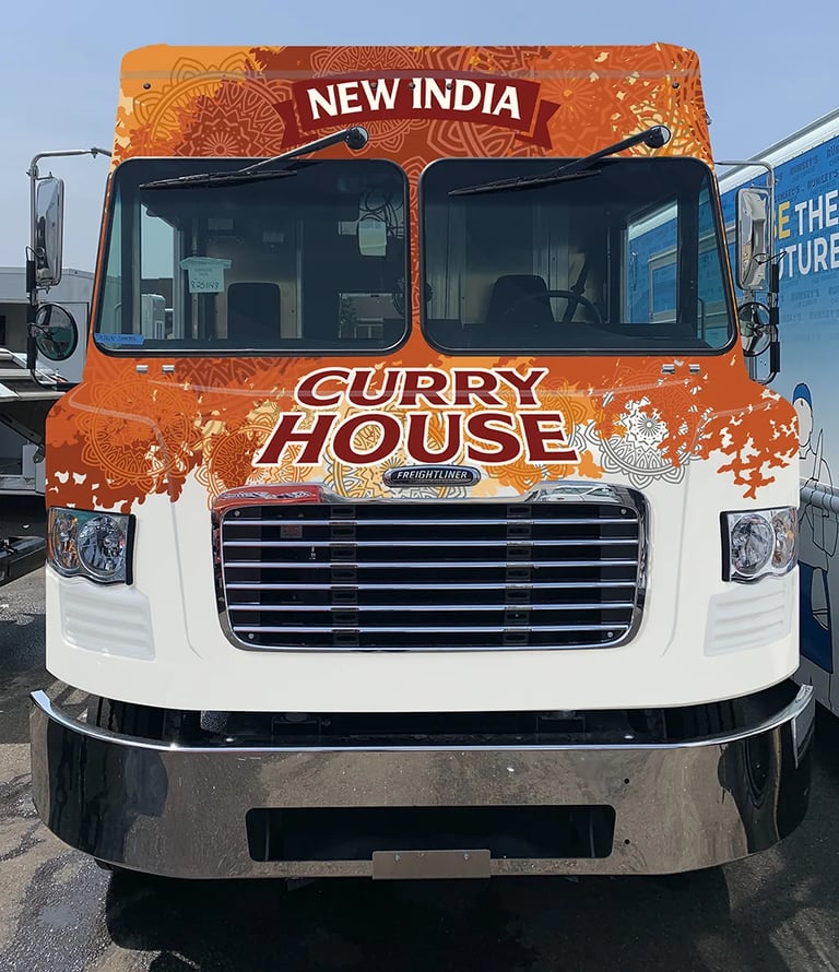 Orange and white food truck labeled New India Curry House with decorative patterns on the side