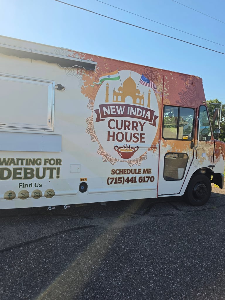 New India Curry House food truck with white and rustic red exterior, featuring logo and contact information for catering bookings